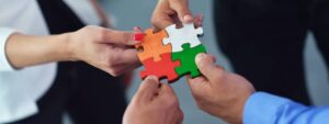 4 team members holding 4 puzzles pieces together