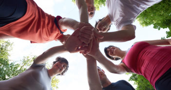 team of people with hands in the middle standing in a circle